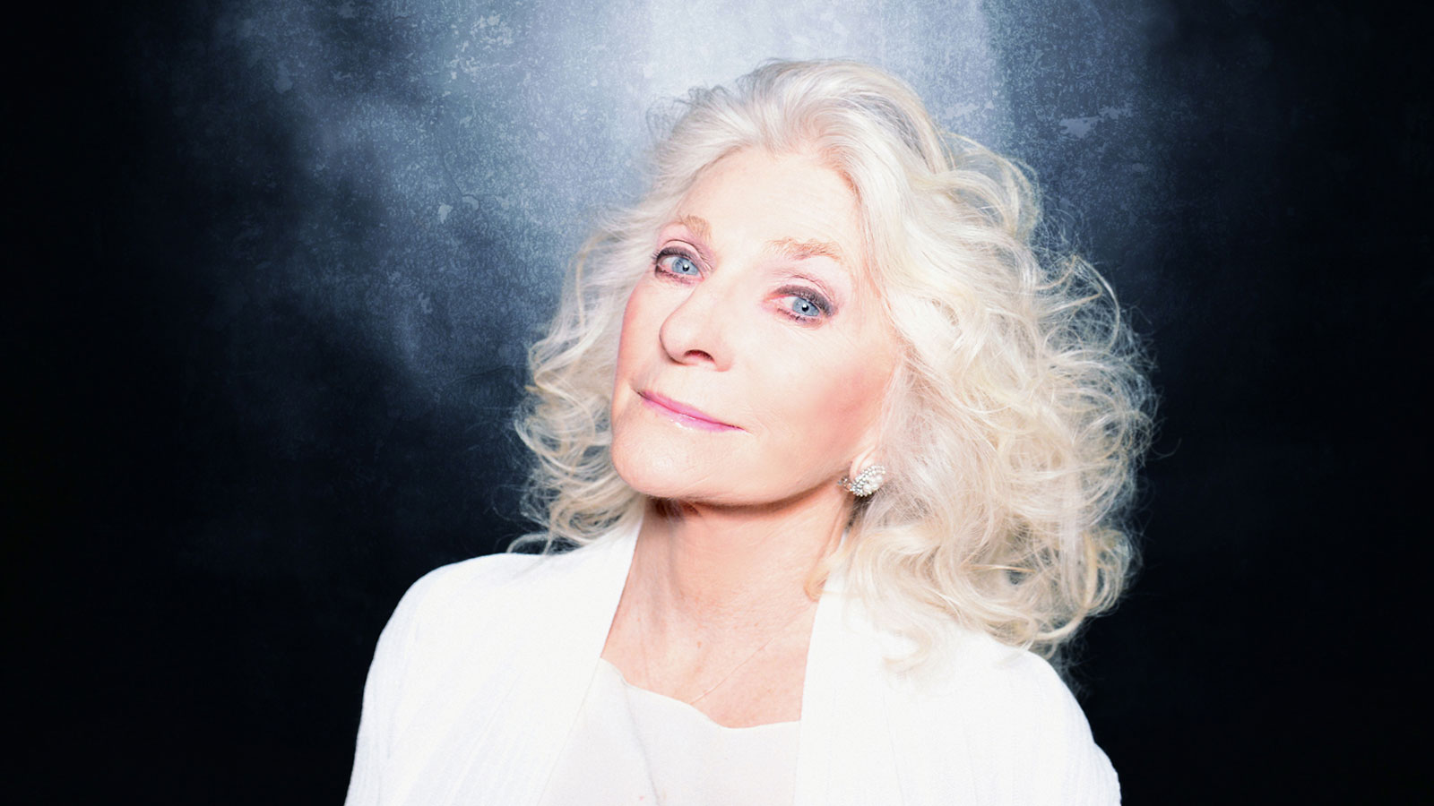 Headshot of Judy Collins dressed in white.