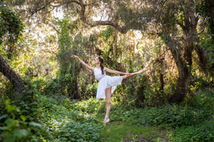 A dancer posing in front of willow tree.