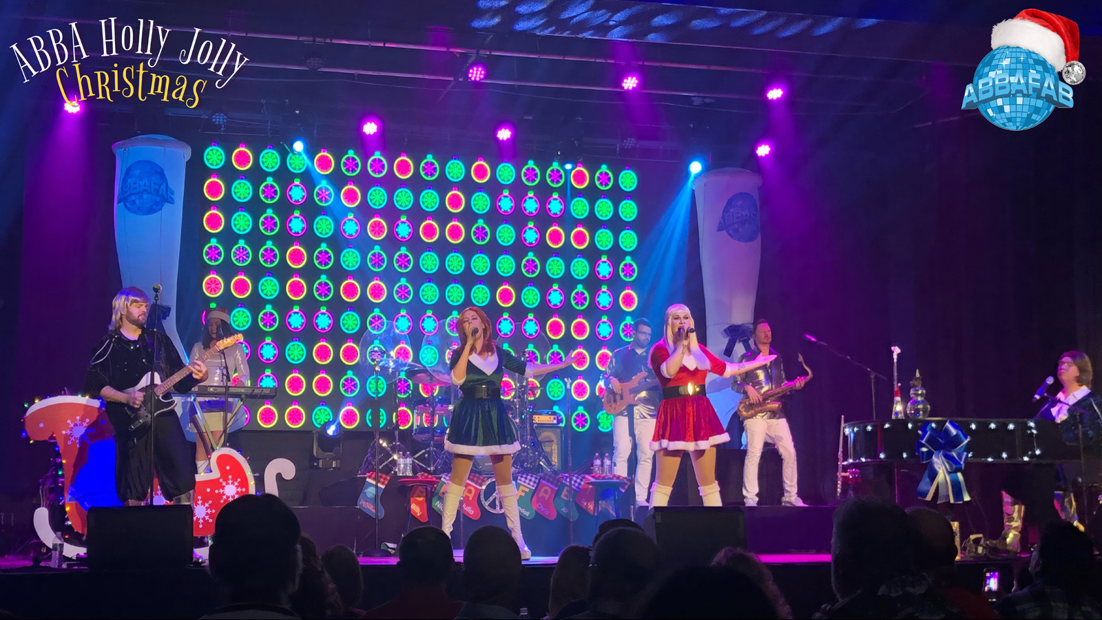 Members of AbbaFab perform on a Christmas-themed stage.