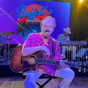 Singer as Jimmy Buffett posed with guitar.