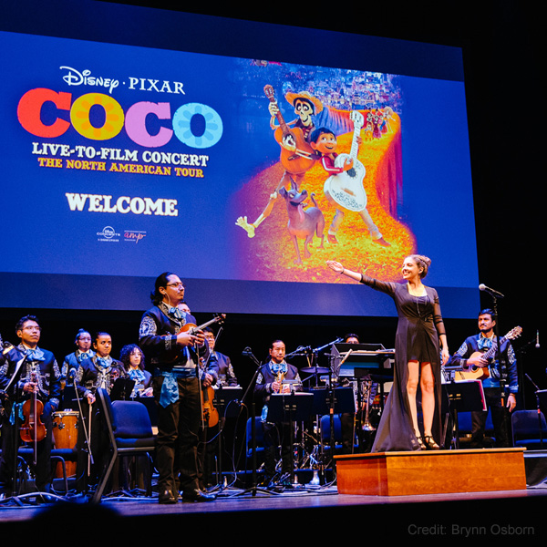 Members of the Coco in Concert orchestra on stage in front of Coco film screen.