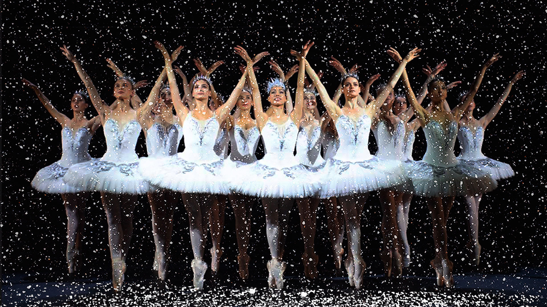 Ballet dancers lined in formation with snow falling in the foreground.