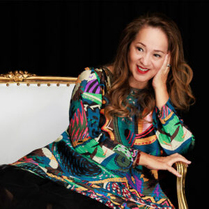 Perla Batalla smiling while seated on a sofa.